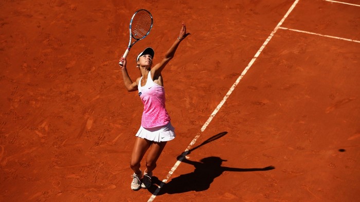 Anna Kalinskaya serving on a clay tennis court