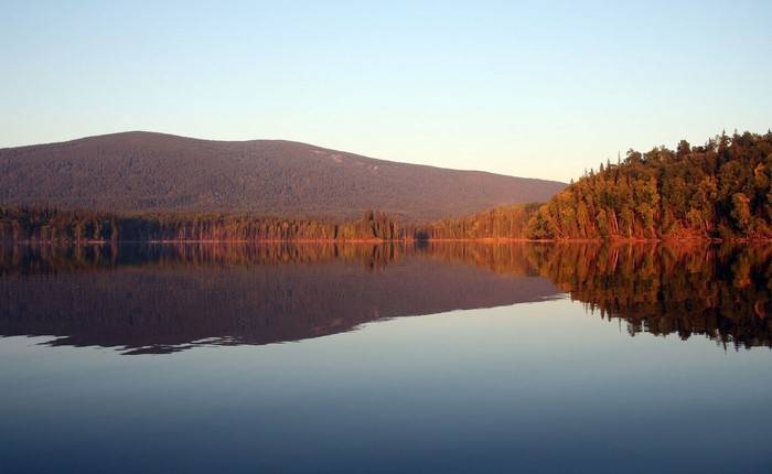 Lake reflection of forest and mountain at sunrise