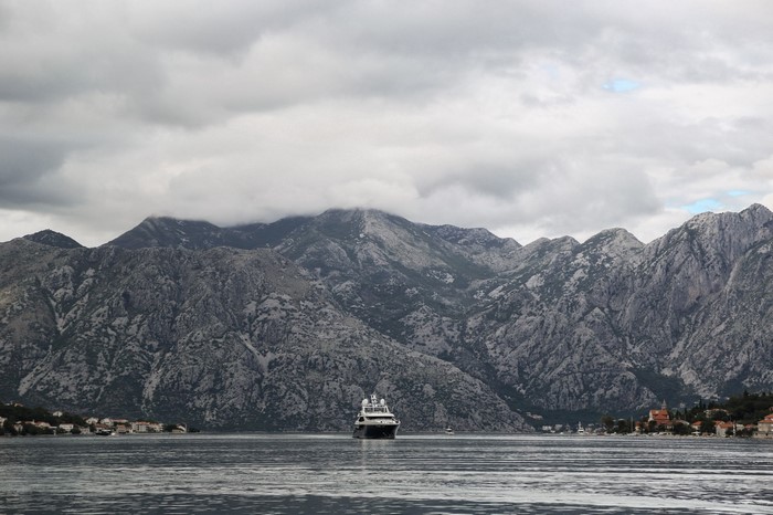 Yacht in a bay with mountains and a coastal town