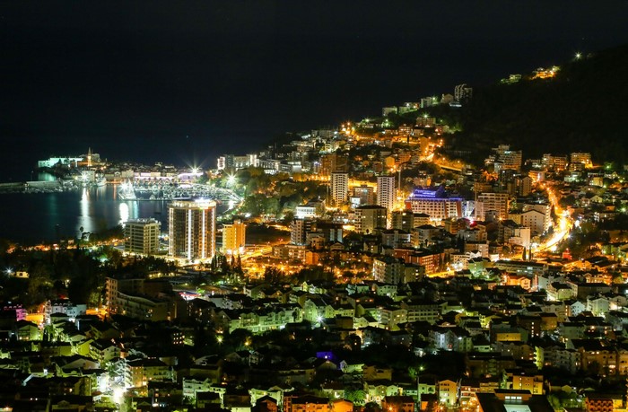 Cityscape at night with illuminated buildings and a harbor