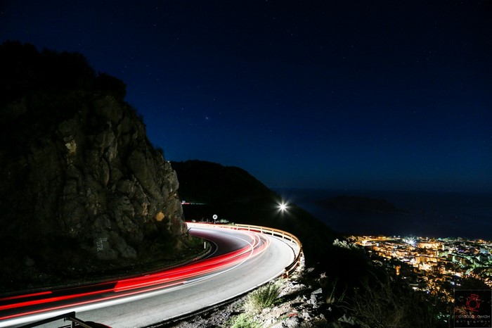 Night road with light trails overlooking a coastal city