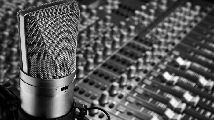 Monochrome close-up of a studio microphone and mixing console