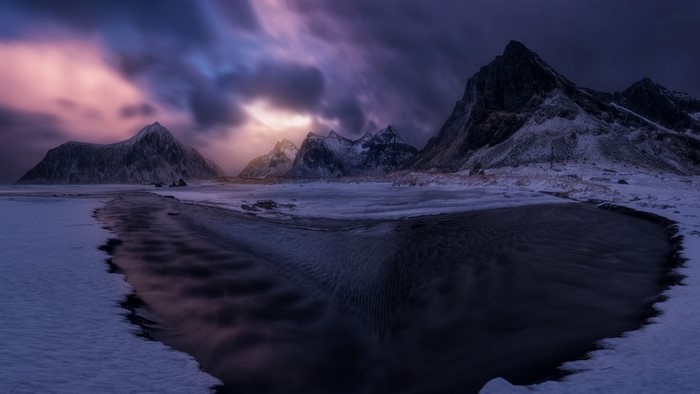 Snowy mountains and beach at dusk in Lofoten Islands