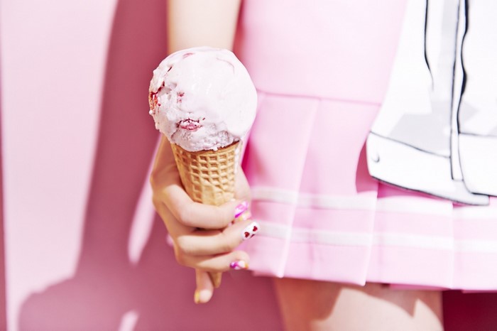 Person holding strawberry ice cream in a pink skirt