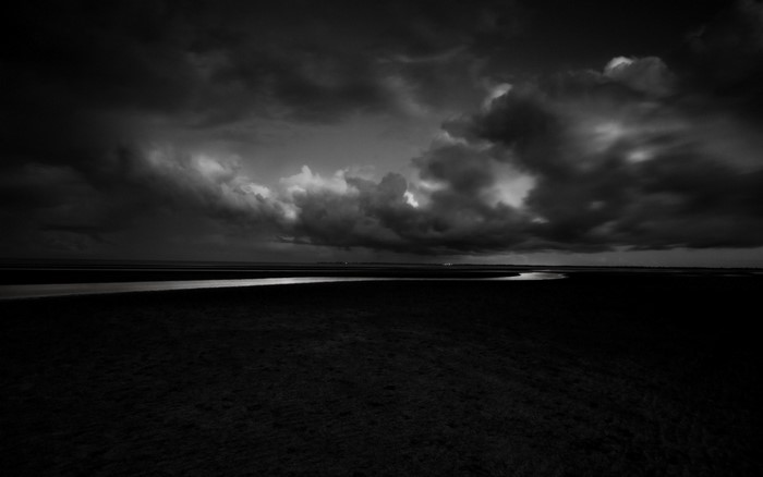 Monochrome landscape with stormy clouds over a river at night