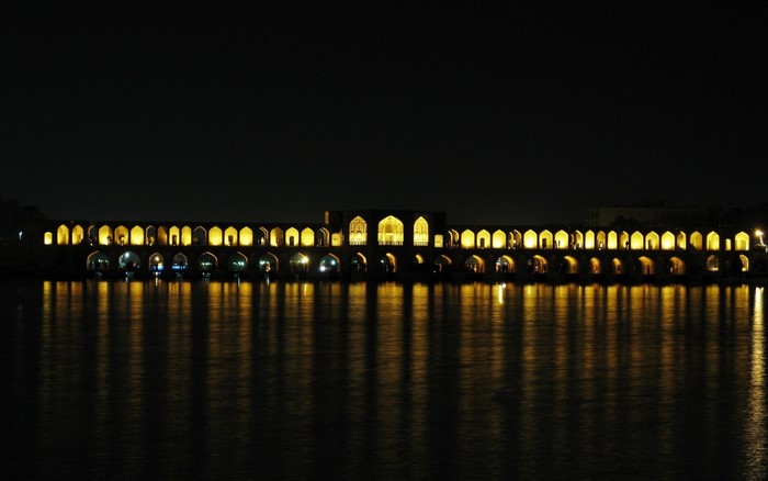 Bridge with arches illuminated at night over water