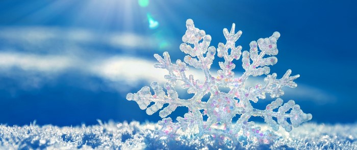 Close-up of a sparkling snowflake on a snowy surface