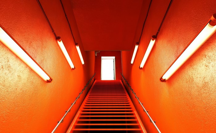 Orange hallway with fluorescent lights and stairs