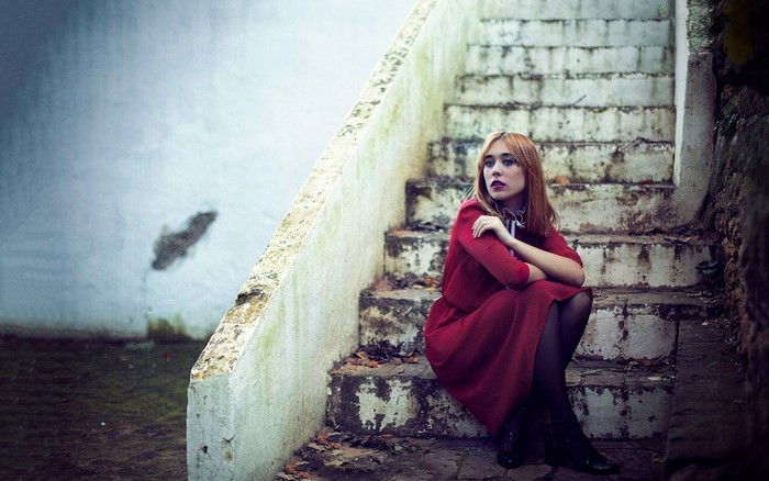 Woman in red dress sitting on outdoor stairs
