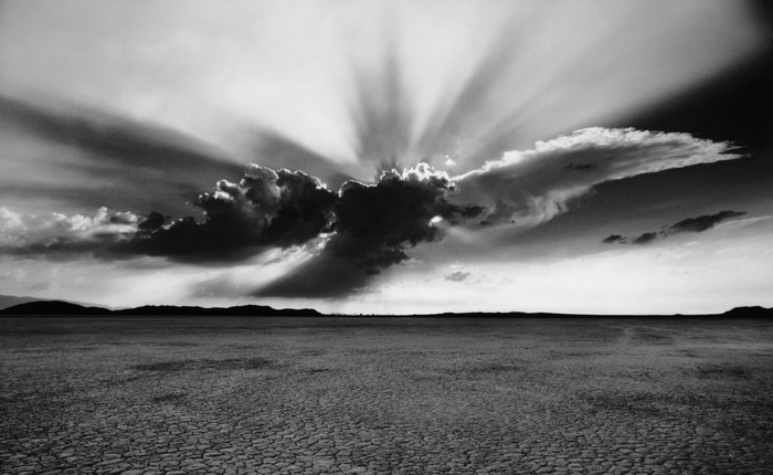 Sunbeams breaking through clouds over a dry lakebed