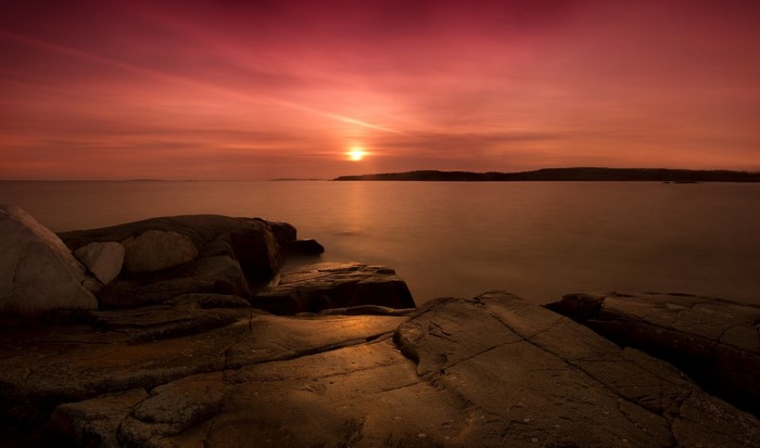 Sunset over the sea with rocks in the foreground