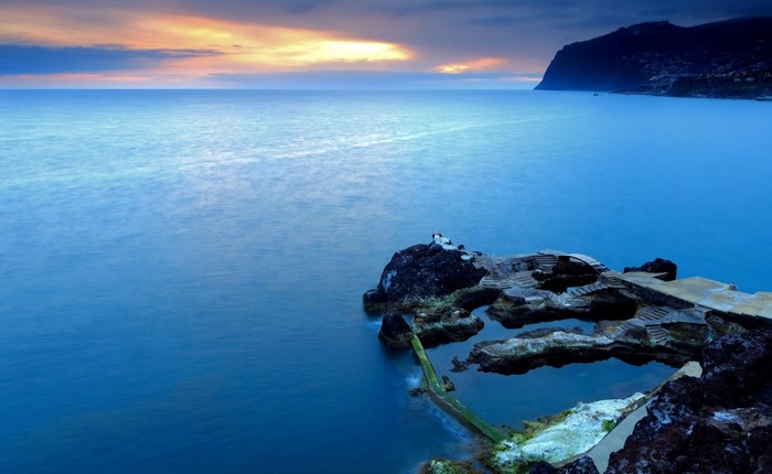 Ocean sunset with rocky shore and swimming pools