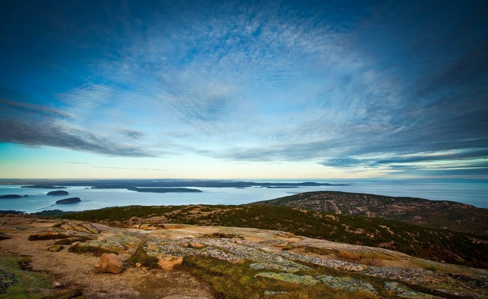 Rocky hill overlooking ocean and islands at sunrise