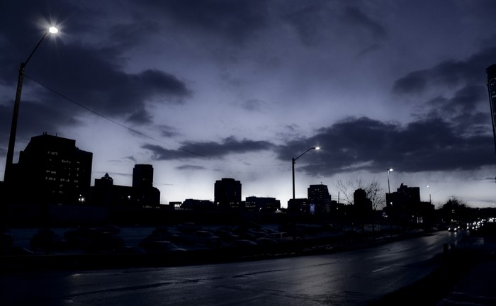 City skyline at dusk with streetlights and clouds