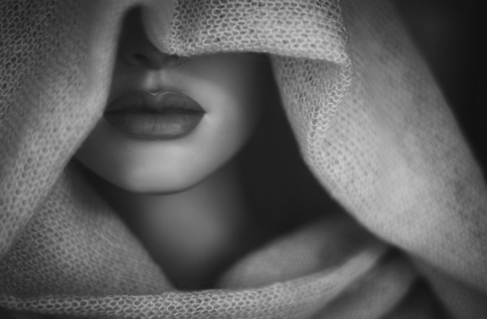 Monochrome close-up of a woman's face covered by fabric