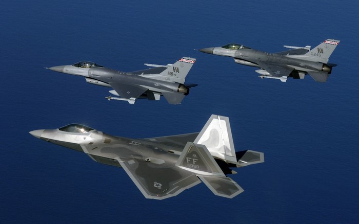 F-22 Raptor and F-16 Fighting Falcons flying over the ocean