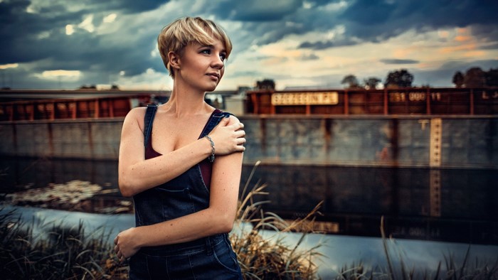 Woman in denim overalls posing by a barge