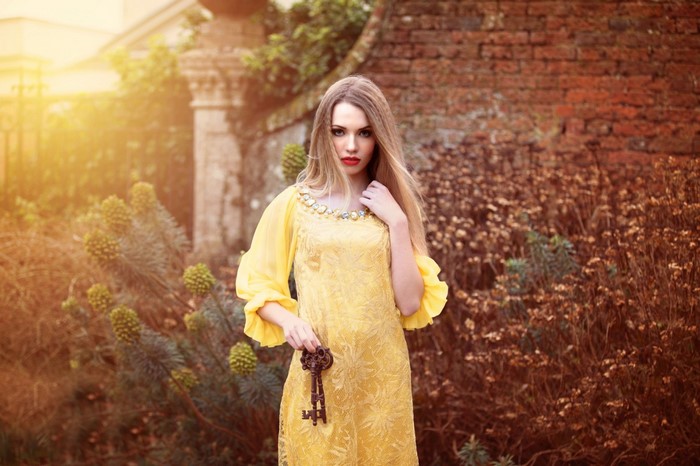 Woman in yellow dress holding a key outdoors