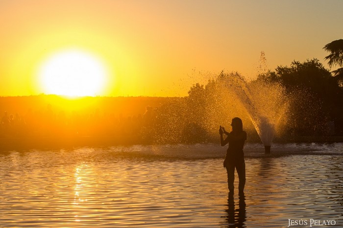 Woman taking a photo of a fountain at sunset