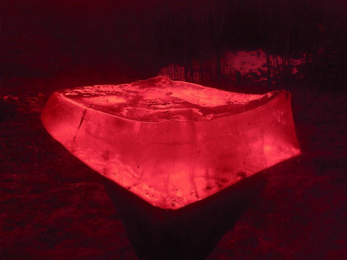 Red ice sculpture illuminated in darkness