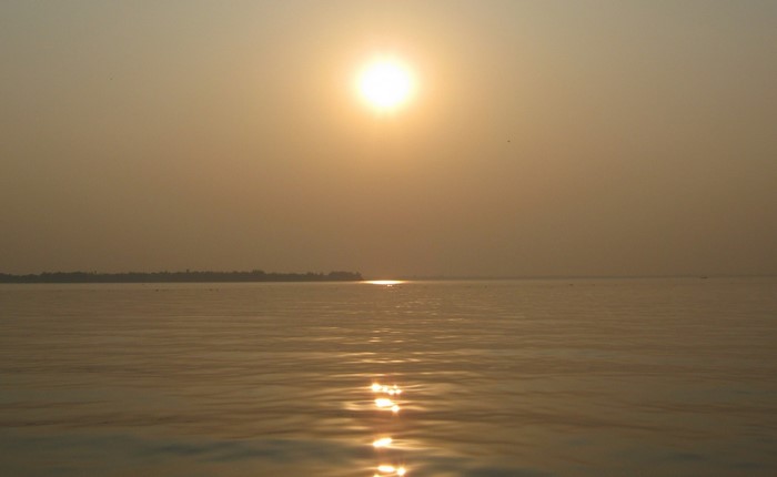 Sunset over a calm body of water with a distant shoreline