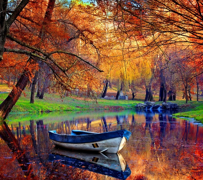 Boat on a pond with autumn trees and reflections
