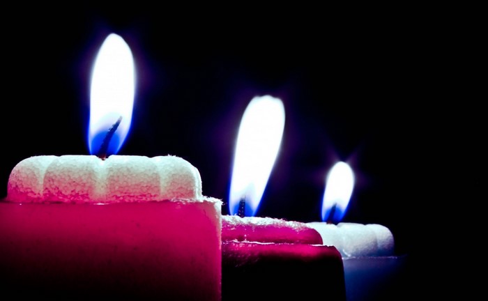 Three lit candles with blue and white flames
