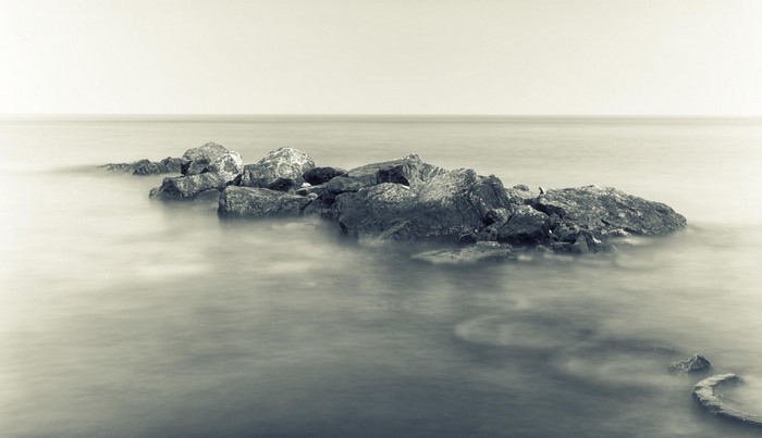 Monochrome photograph of rocks in the sea