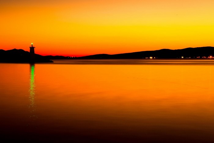 Lighthouse reflecting on the sea at sunset
