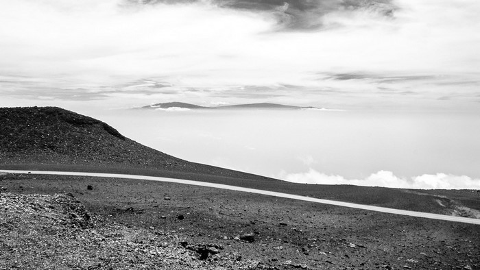Mountain road above clouds with distant islands