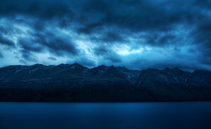 Dark Mountains over a Calm Lake Under Stormy Clouds