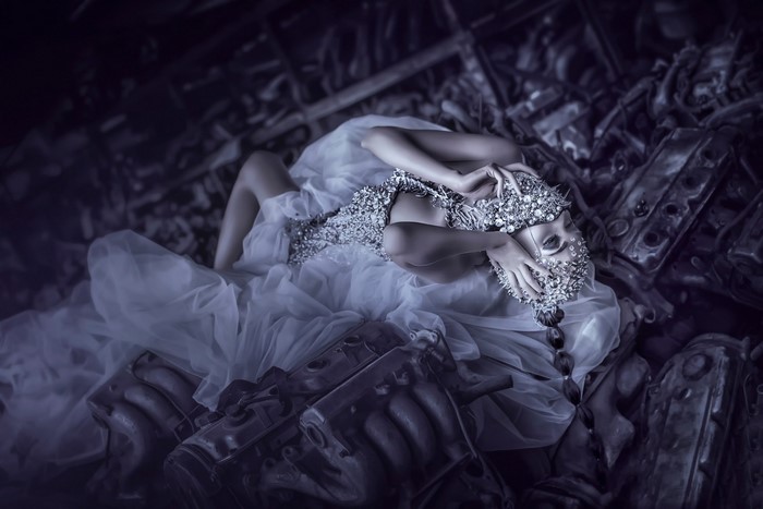 Woman in white dress with ornate headpiece lying in debris
