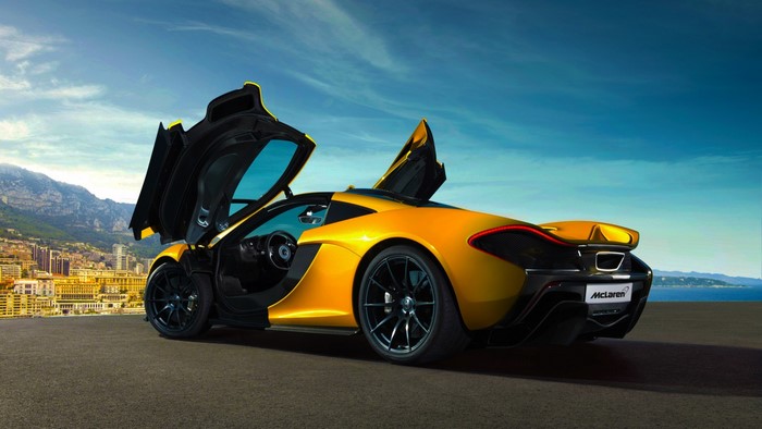 Yellow McLaren sports car with doors open in a coastal city