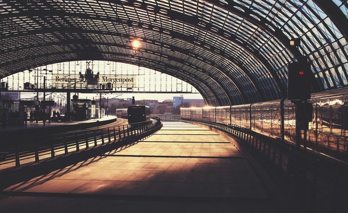 Berlin train station with trains and glass roof at sunset