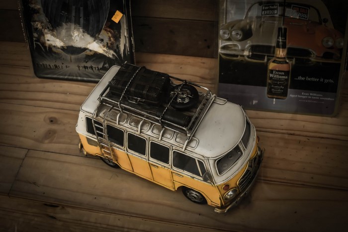 Yellow and white toy van with luggage on roof
