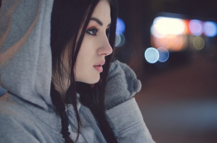 Woman in a grey hoodie looking away at night