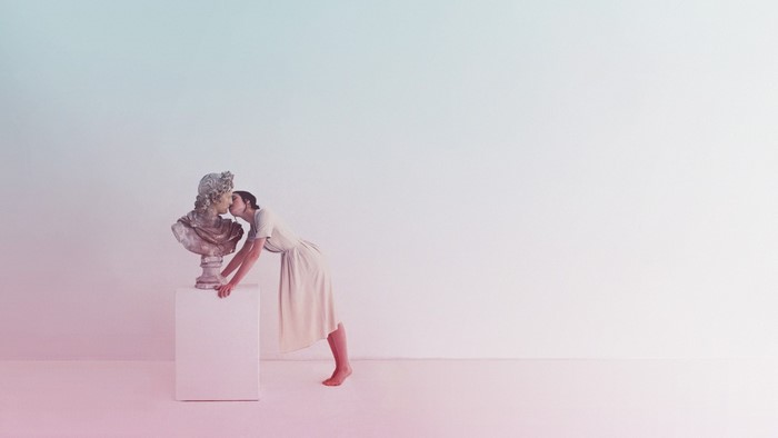 Woman kissing a bust on a pedestal