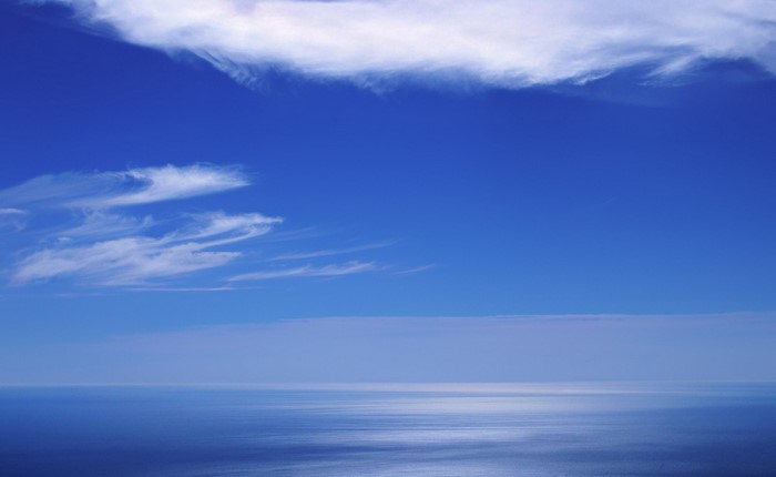 Blue sky with clouds over the ocean horizon