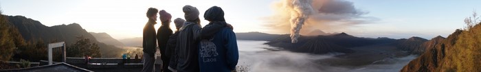 Group of friends watching a volcanic eruption at sunrise