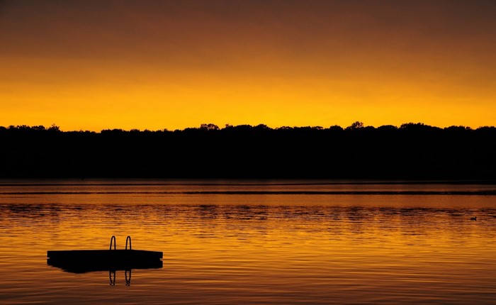 Sunset over a calm lake with a dock