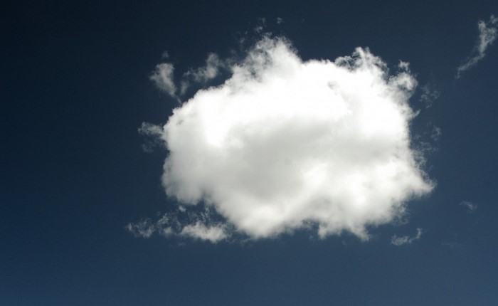 A single white cumulus cloud in a dark blue sky