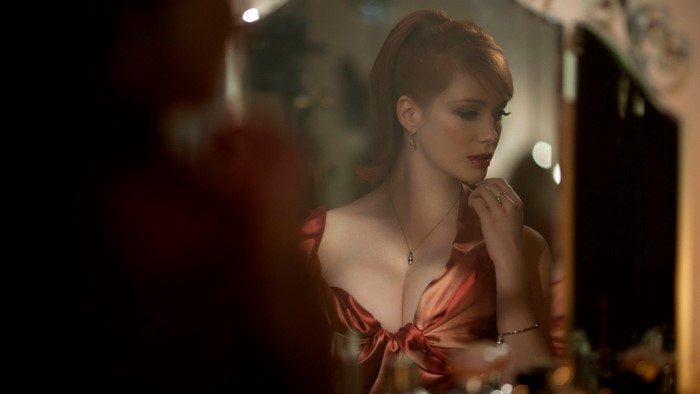 Christina Hendricks in a red dress looking in a mirror