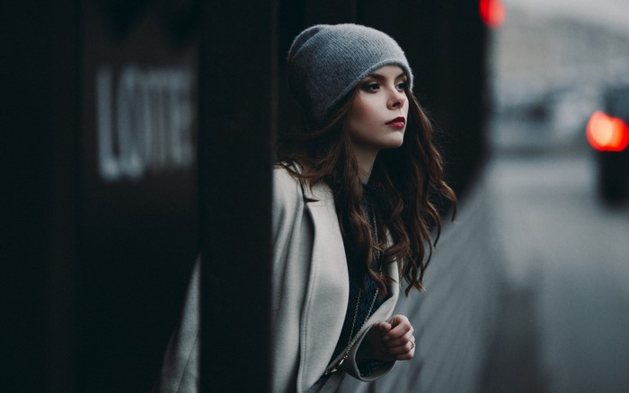 Woman in a gray beanie and coat looking away
