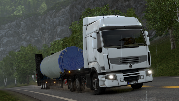 White truck carrying a large cylindrical object on a trailer