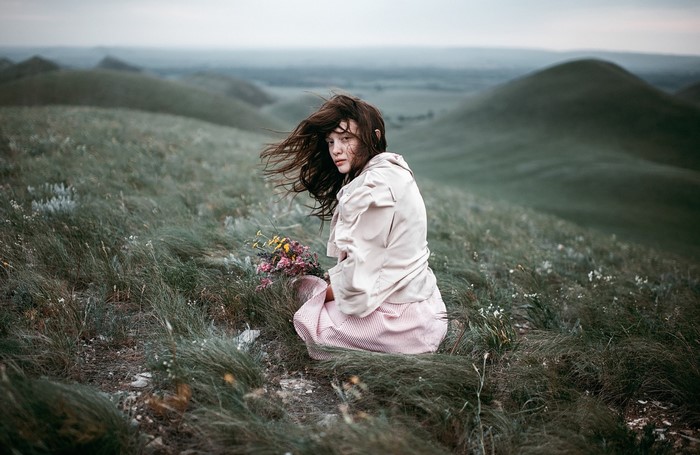 Woman with flowers in a grassy landscape
