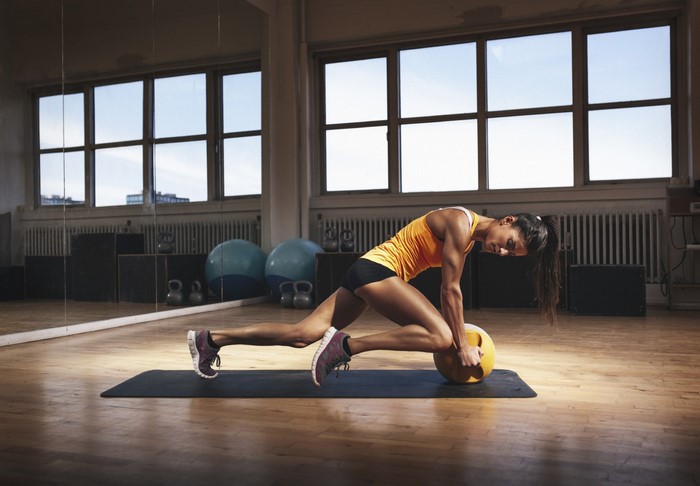 Woman performing mountain climbers with a medicine ball