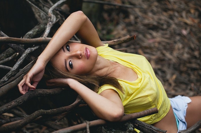 Woman in yellow shirt lying on branches