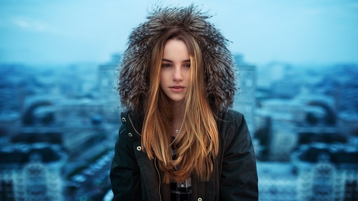 Woman with long brown hair wearing a fur-hooded jacket