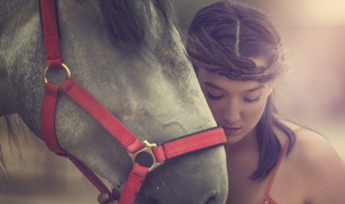 Woman with braided hair leaning on a horse