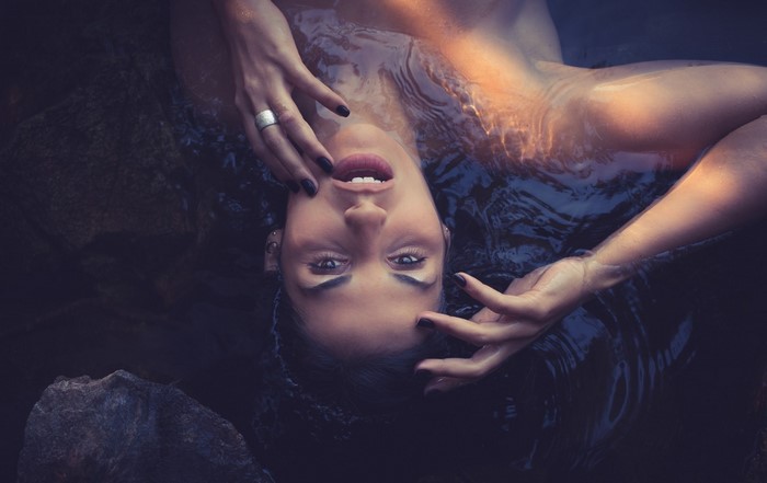 Woman lying in dark water with light on her face